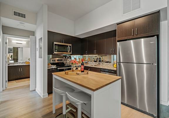 A modern kitchen with a wooden island and stainless steel appliances.