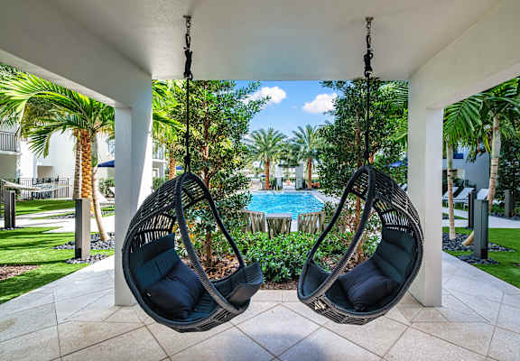 Two hanging chairs are suspended from a covered patio area.