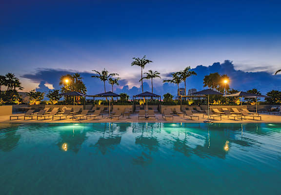 a large swimming pool with chaise lounges and palm trees at night at Regatta at New River, Fort Lauderdale, FL