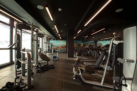 A gym with a variety of equipment including treadmills, weights, and exercise machines.