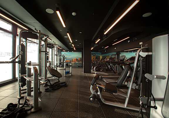 A gym with a variety of equipment including treadmills, weights, and exercise machines.