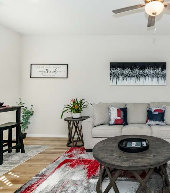 A living room with a white couch and a red rug.