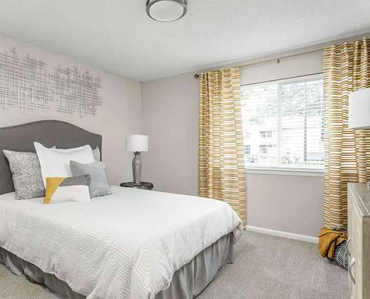 A bedroom with a bed, two lamps, and a window with curtains.