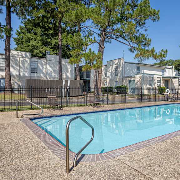 A swimming pool surrounded by a fence and trees.