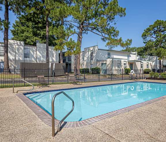 A swimming pool surrounded by a fence and trees.