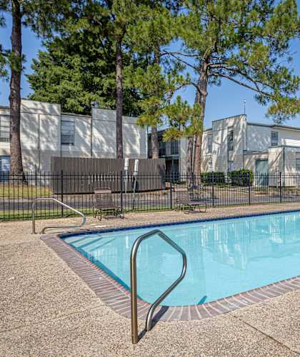 A swimming pool surrounded by a fence and trees.
