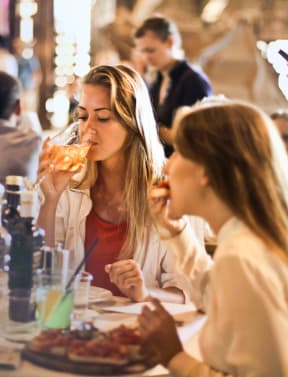 two women sitting at a table in a restaurant eating food and drinking wine at Missouri Crossing, Phoenix, Arizona