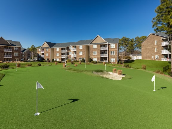 a putting green with apartments in the background