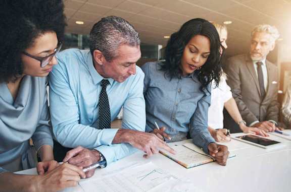 A group of people in a meeting room with documents on the table.