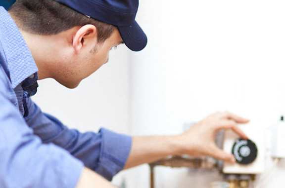 A man in a blue shirt and cap is adjusting a black device.
