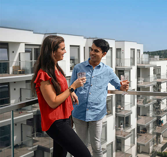 Two people standing on a balcony with apartment buildings in the background at Cherrywood Apartments, D18 VY3V, DUBLIN 18