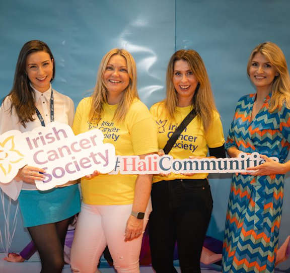 Four women wearing yellow Irish Cancer Society t-shirts are standing together.