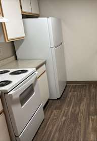 A kitchen with a white refrigerator and a stainless steel sink.