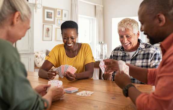A group of people playing a card game at a table.