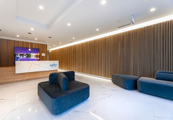 A modern waiting area with a wooden wall and a white reception desk.