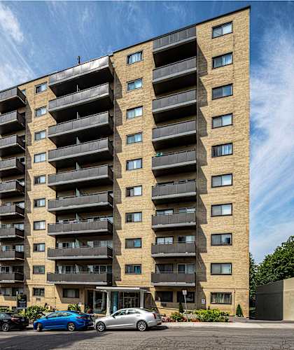 A tall apartment building with cars parked in front.