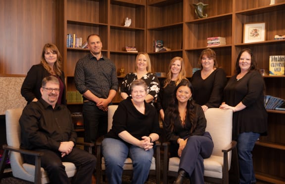 a group of people sitting and standing in front of a bookshelf