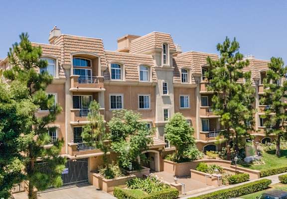 A large, multi-story residential building with a courtyard and trees.