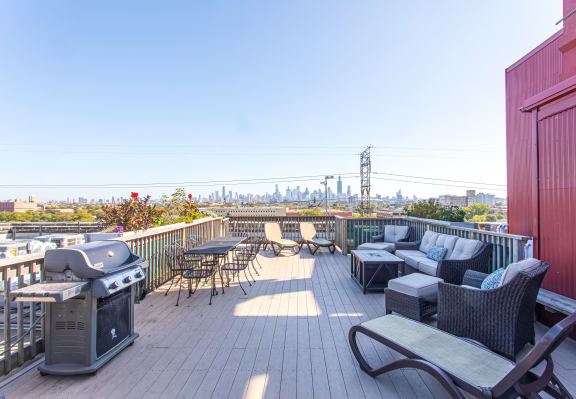 a rooftop deck with furniture and a city in the background