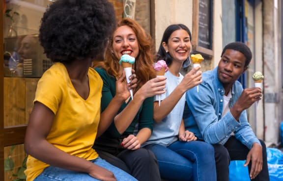 a group of people sitting on a bench eating ice cream