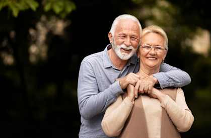 an elderly couple posing for a photo with their arms around each other