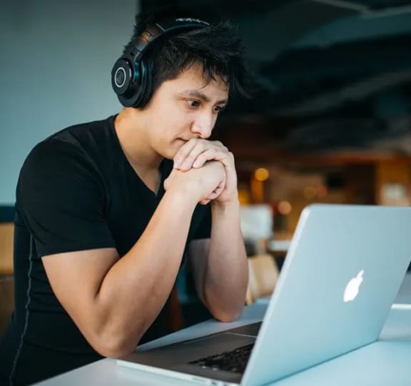 a man wearing headphones looking at a laptop computer