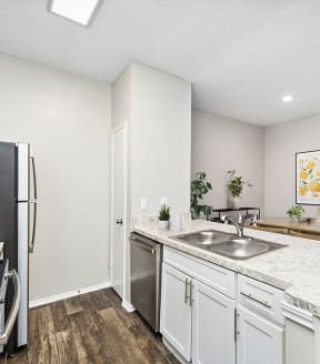 Model Kitchen with White Cabinets and Wood-Style Flooring at Dallas North Park Apartments in Dallas, TX-SMLAM.