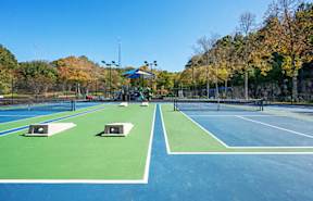 a group of tennis courts in a park with trees