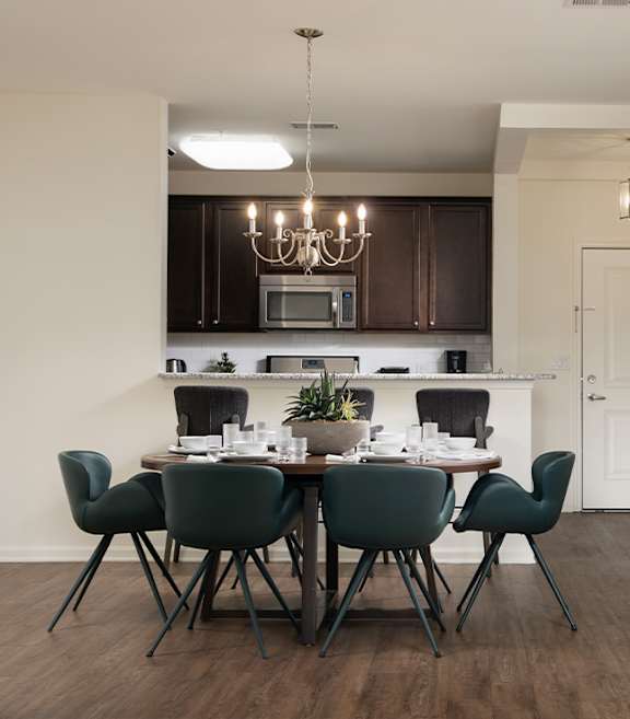 A dining room with a table set for six and a chandelier hanging from the ceiling.
