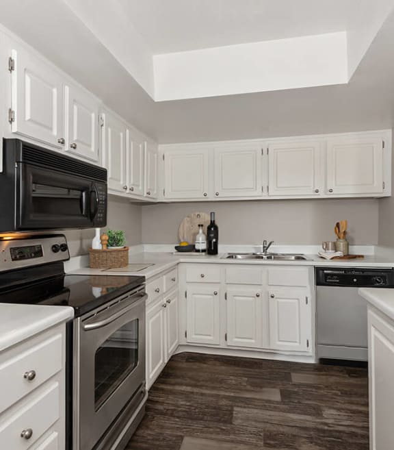 Model Kitchen with White Cabinets and Wood-Style Flooring at Saratoga Ridge Apartments located in North Phoenix, AZ-SMLAM.