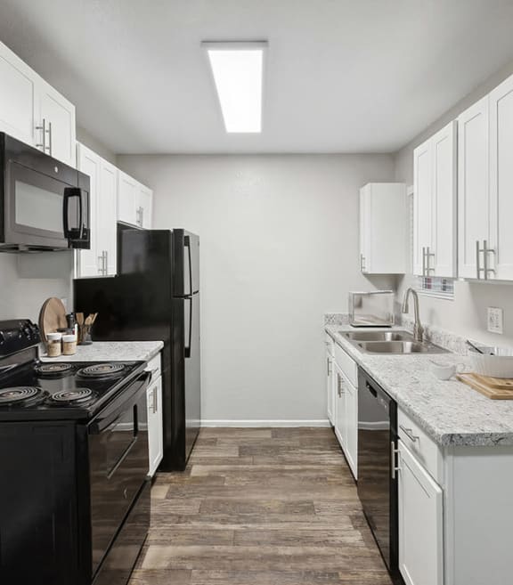 Model Kitchen with White Cabinets and Wood-Style Flooring at Solano Springs Apartments located in Tucson, AZ-SMLAM.