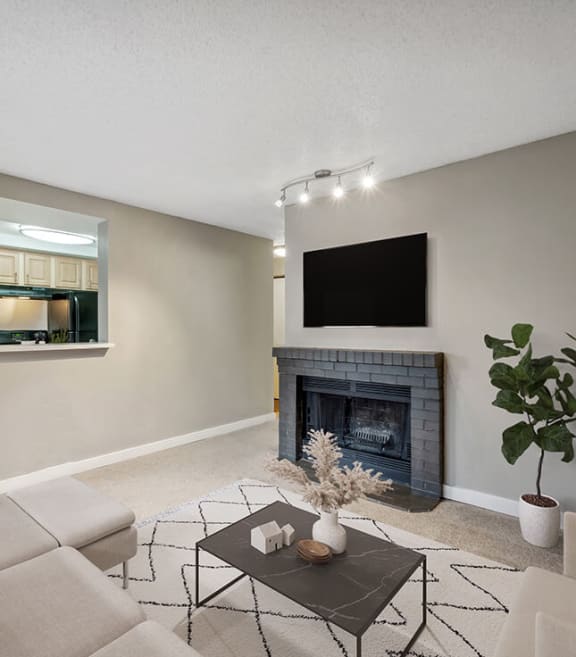 Model Living Room with Carpet, Fireplace and View of Kitchen at Grammercy Apartments located in Renton, WA-SMLAM.