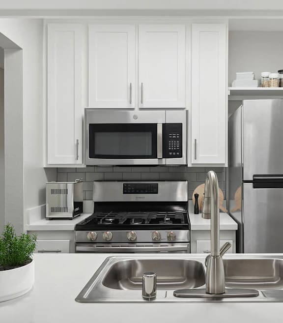 Model Kitchen with White Cabinets and Wood-Style Flooring at Fullerton Hills Apartments located in Fullerton, CA-SMLAM.