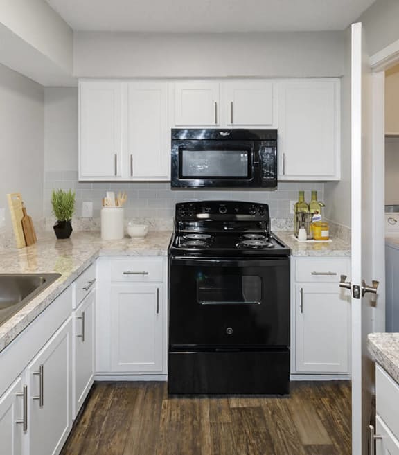 Model Kitchen with White Cabinets and Wood-Style Flooring at Cobblestone Apartments in Arlington, TX-SMLAM.