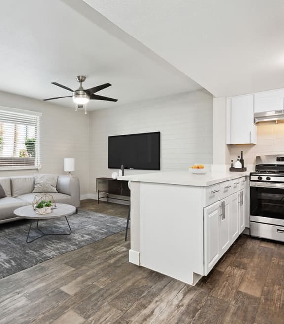 Model Kitchen with White Cabinets, Wood-Style Flooring and View of Living Room at Arcadia on 49th Apartments located in Phoenix, AZ-SMLAM.