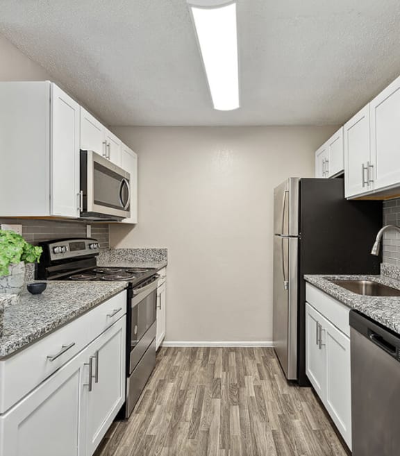 Model Kitchen with White Cabinets and Wood-Style Flooring at Park at 7200 Apartments in Jacksonville, FL-SMLAM.