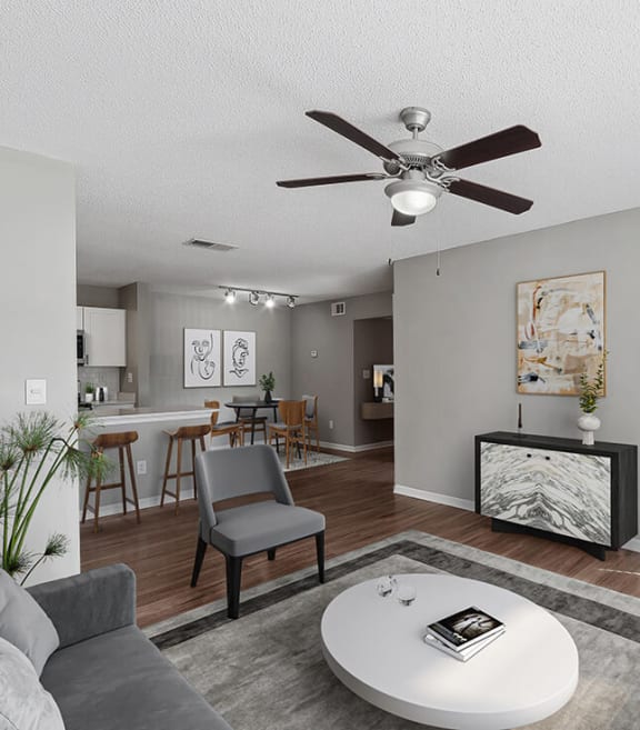 Model Living Room with Wood-Style Flooring and View of Kitchen/Dining Area at Fountains Lee Vista Apartments in Orlando, FL.