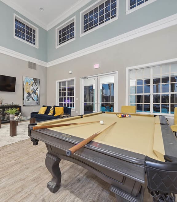 Community Clubhouse with Lounge Furniture and Pool Table Area at Vinings at Hunter's Green Apartments in Tampa, FL.