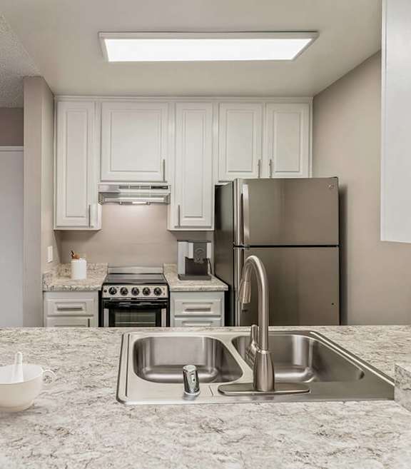 Model Kitchen with White Cabinets and Wood-Style Flooring at Crystal View Apartments located in Garden Grove, CA.