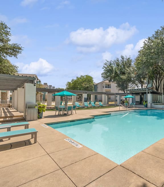 Community Swimming Pool with Pool Furniture at Essence Apartments in Dallas, TX.