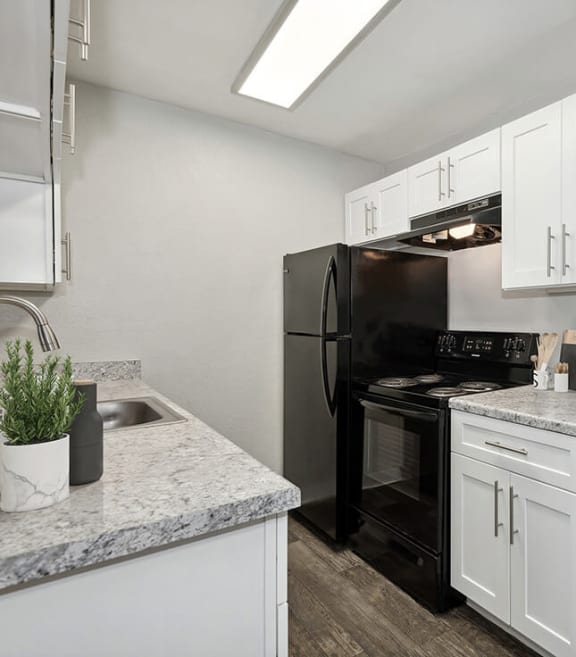Model Kitchen with White Cabinets and Wood-Style Flooring at Stillwater Apartments in Glendale, AZ-SMLAM.