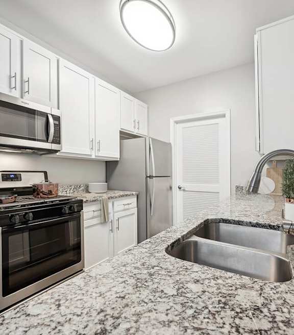 Model Kitchen with White Cabinets and Wood-Style Flooring at Dulles Green Apartments located in Herndon, VA-SMLAM.