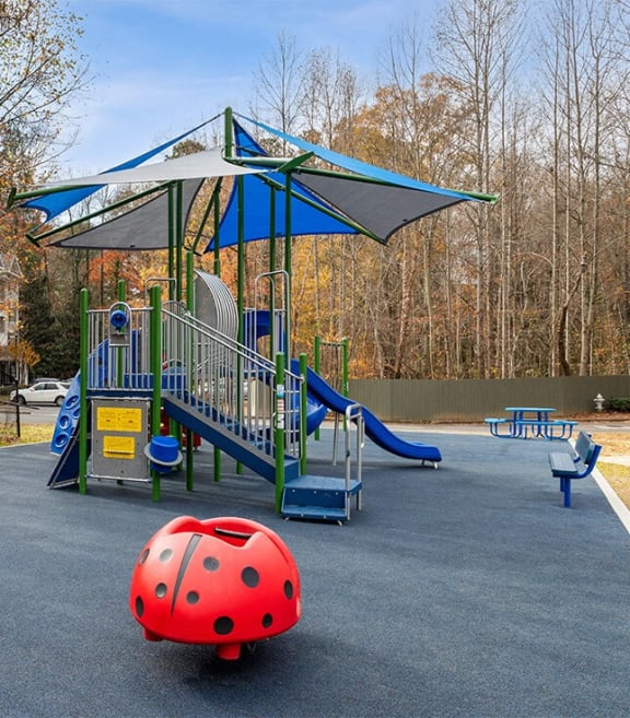 a playground with a ladybug toy and a swing set