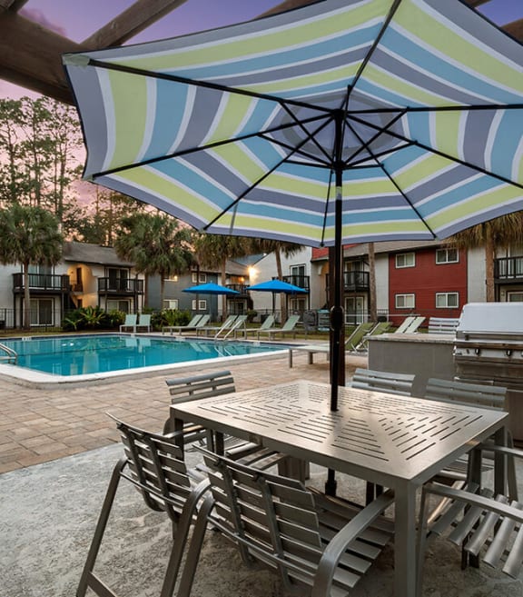 Outdoor BBQ Area with Furniture and Pool View at Heron Walk Apartments in Jacksonville, FL-SMLAM.
