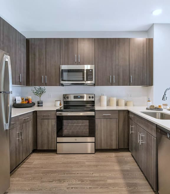 Model Kitchen with Dark Wood Cabinets and Wood-Style Flooring at Glen 91 Apartments located in Glendale, AZ-SMLAM.