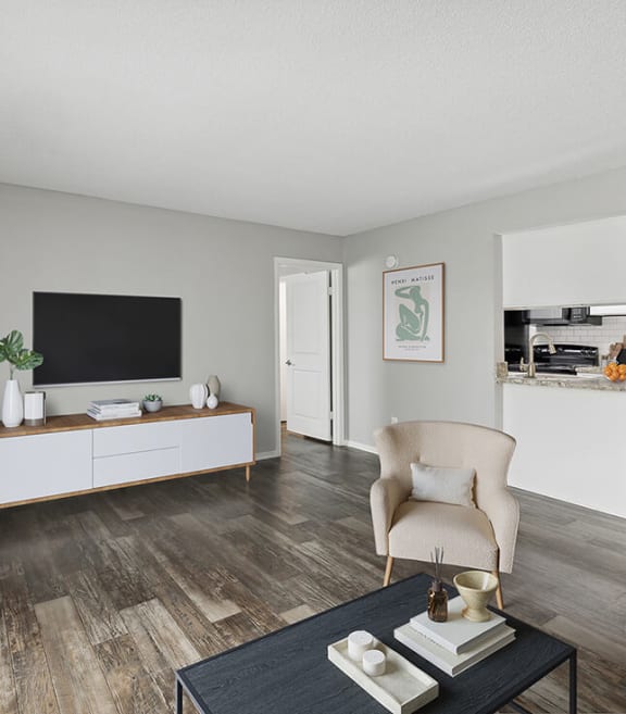 Model Living Room with Wood-Style Flooring and View of Kitchen at Heron Walk Apartments in Jacksonville, FL-SMLAM.