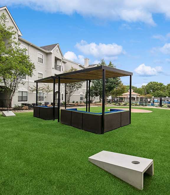 Outdoor Corn Hole Area and Lounge Furniture at Hidden Creek Apartments located in Lewisville, TX.