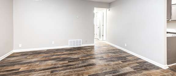 an empty living room with white walls and wood flooring