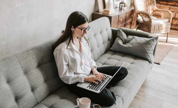 a woman sitting on a couch using a laptop computer