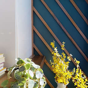 A vase with yellow flowers sits on a wooden table.